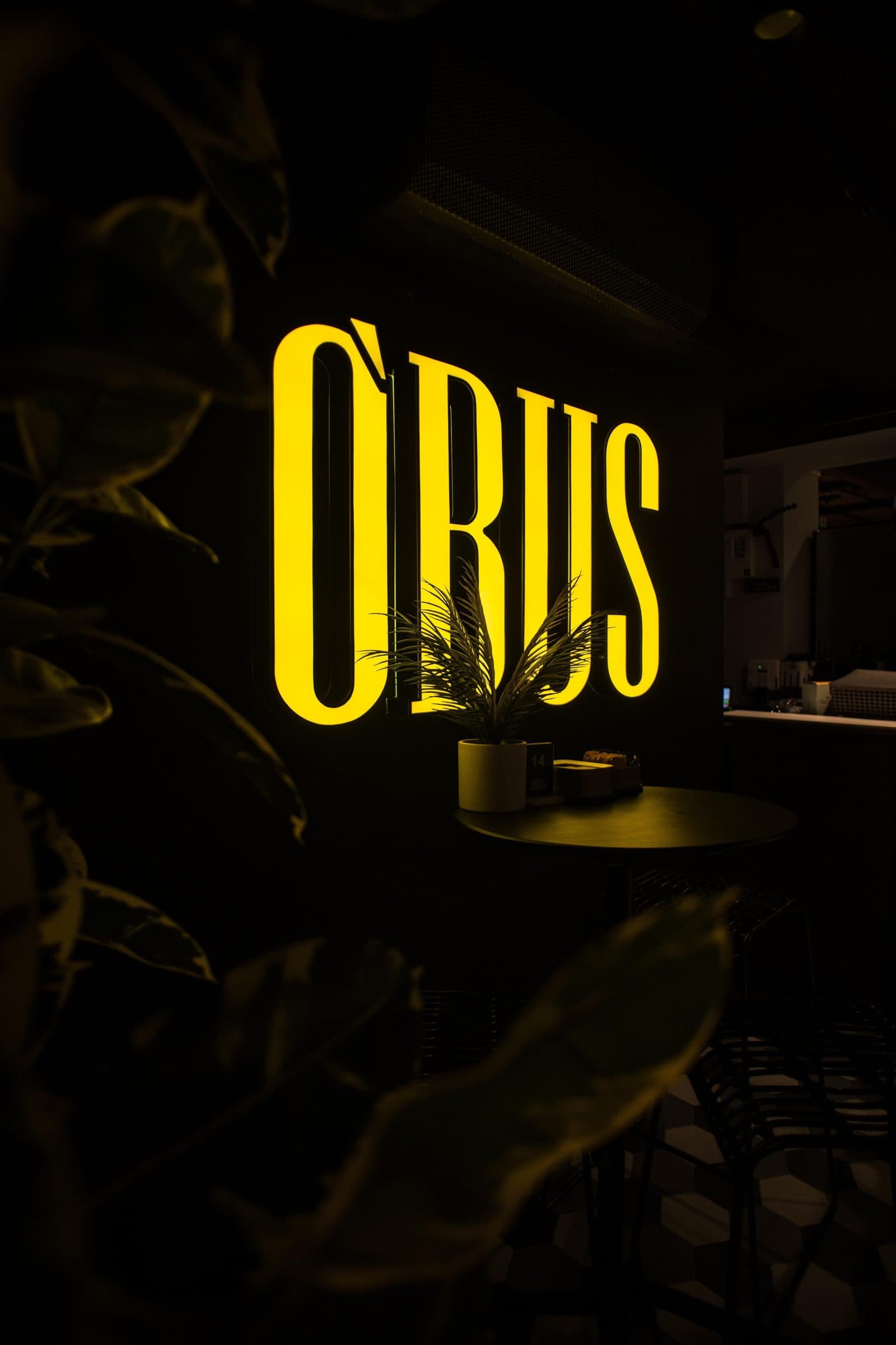 L'insegna al neon di OBUS tra le piante